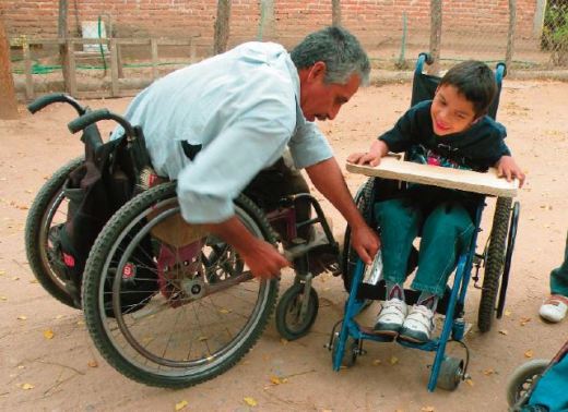 Raymundo, leader of the PROJIMO Duranguito workshop, adjusts a wheelchair that the team made for this boy.